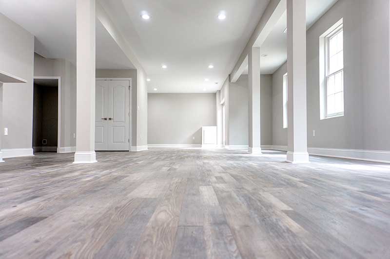 Interior de un piso vacío reformado con columnas y suelo de madera gris