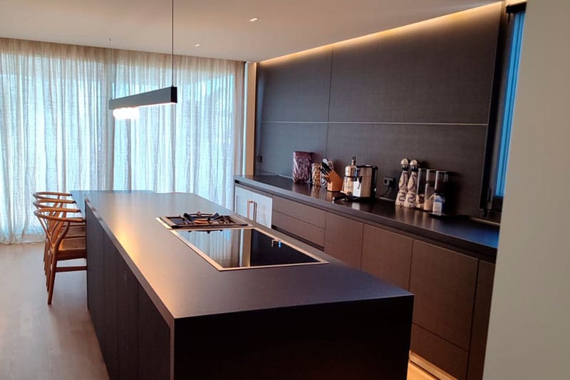 Cocina negra de diseño con isla central en ático reformado en la Bonanova, Barcelona.