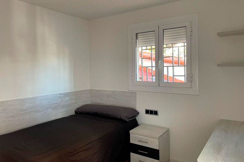 Dormitorio individual reformado con ventana y mobiliario moderno en Chinchón.