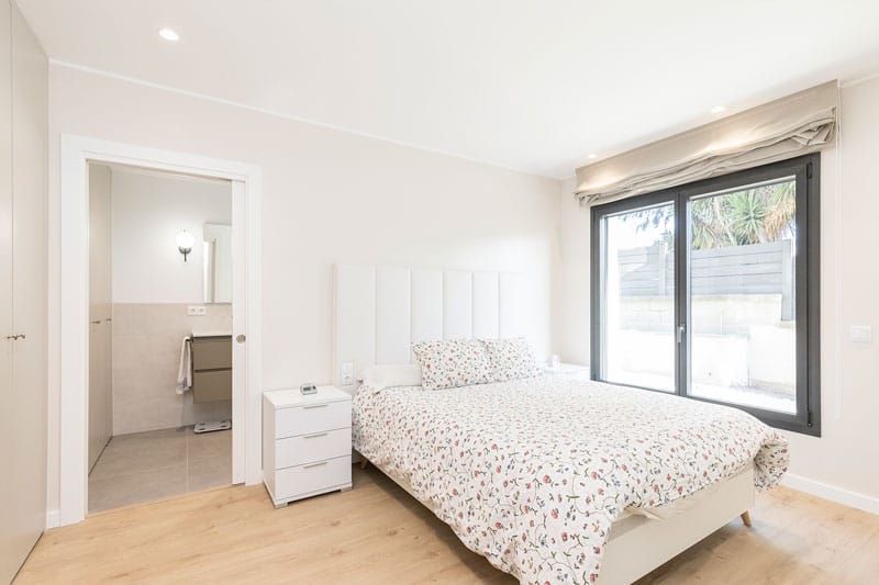 Dormitorio principal con baño en suite y acceso al jardín en vivienda unifamiliar de obra nueva en Viladecavalls, realizada por Inteco Construcción.