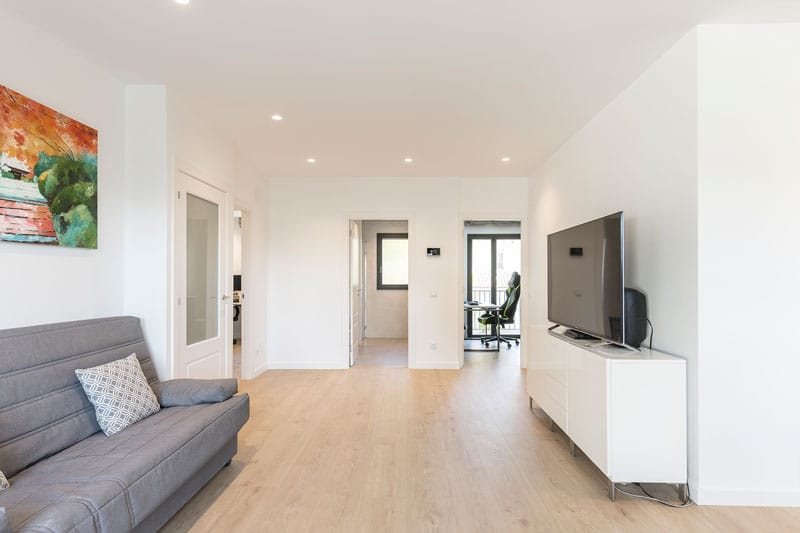 Espacio polivalente con zona de estar, televisión y acceso a despacho en vivienda unifamiliar construida por Inteco Construcción en Viladecavalls.