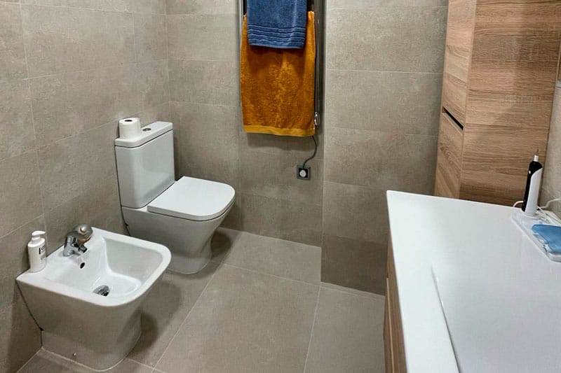 Vista de inodoro y bidé en baño reformado con revestimiento cerámico en Chinchón.