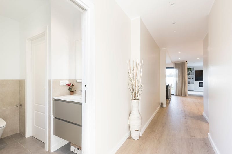 Pasillo luminoso con acceso al baño secundario en vivienda unifamiliar de obra nueva en Viladecavalls, proyecto de Inteco Construcción.